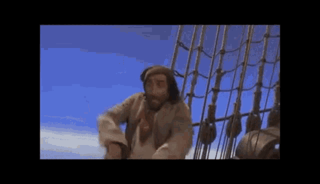 a man with a beard is standing on top of a sailboat .