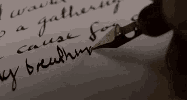 a close up of a person writing a letter with a fountain pen .