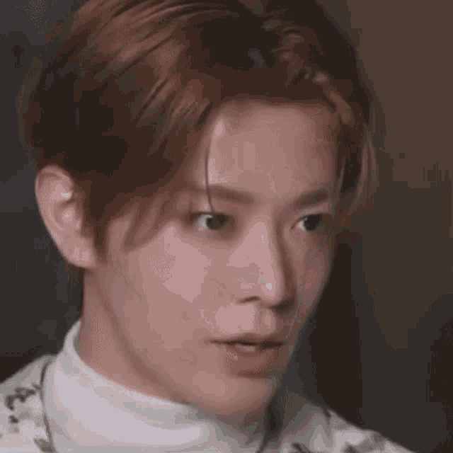 a close up of a young man with red hair wearing a white turtleneck and making a funny face .