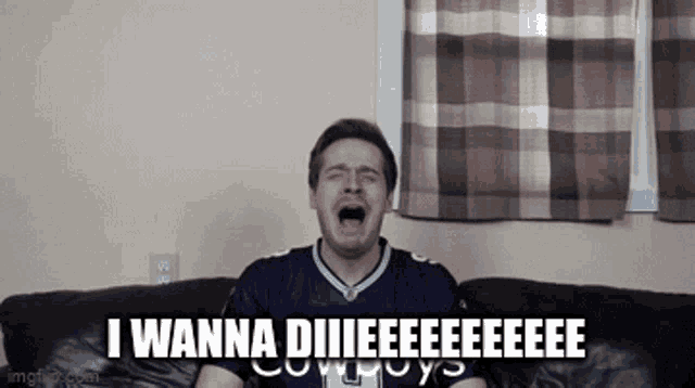 a man in a cowboys jersey is crying while sitting on a couch