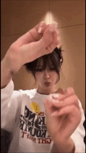 a woman wearing a white shirt with a smiley face is holding a lighter in her hand .