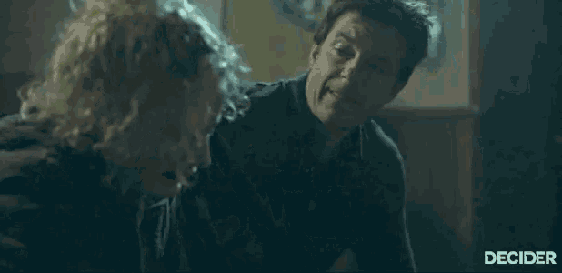 a man is hugging a woman in a dark room with a dartboard in the background .