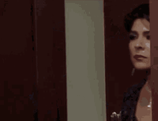 a woman wearing a necklace and earrings is standing in a room .