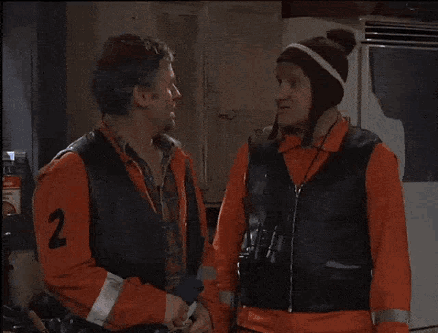 a man in an orange jacket is talking to another man in a black jacket with the words sa dor mor on the bottom
