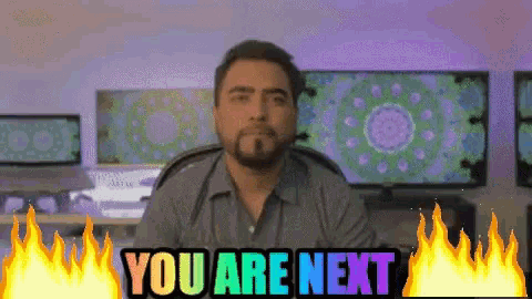 a man is sitting in front of a screen that says you are next
