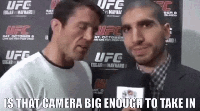 two men are talking in front of a ufc banner