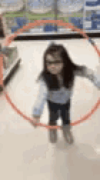 a little girl is holding an orange hula hoop in a store .