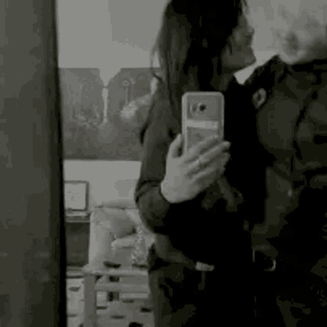 a woman is taking a selfie in front of a mirror while hugging another woman .