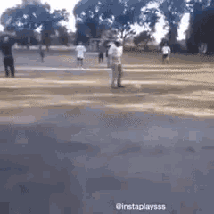 a group of people are standing on a dirt field .