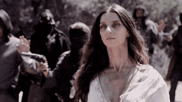 a woman in a white dress is standing in a crowd of people
