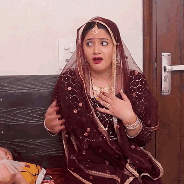 a woman with a veil on her head is sitting on a bed and making a funny face
