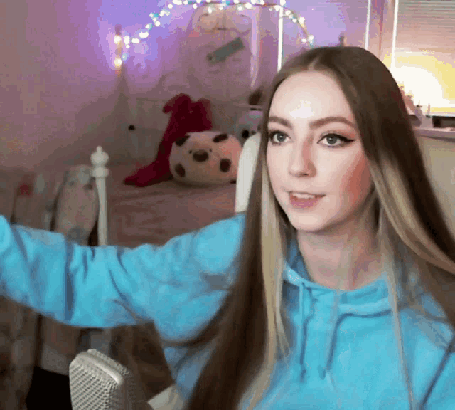 a woman in a blue hoodie takes a selfie in front of a microphone