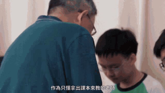 a man in a blue shirt is talking to a young boy in a green shirt