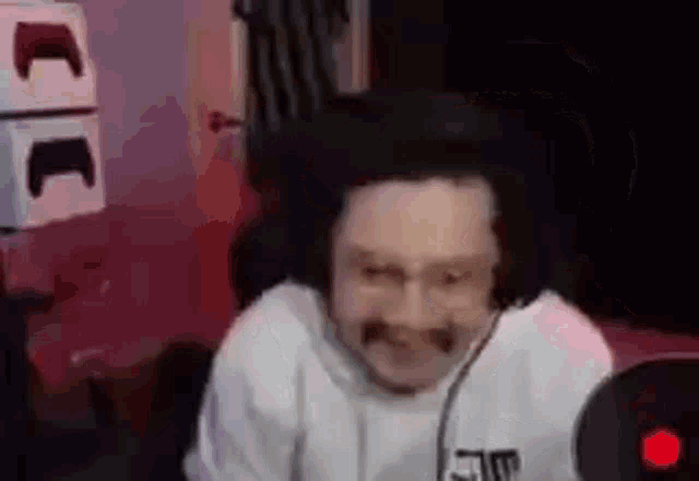 a man with a mustache is sitting in front of a microphone in a room .