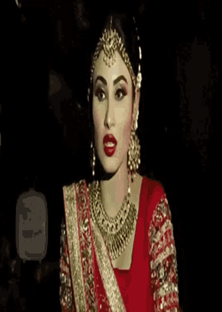 a woman is wearing a red and gold dress and jewelry