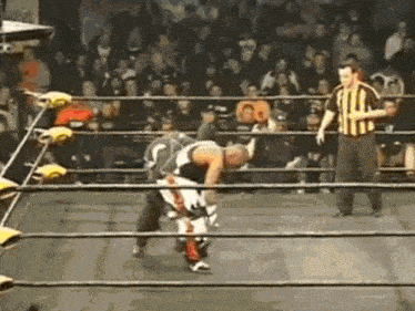 a referee stands in a wrestling ring watching a wrestler