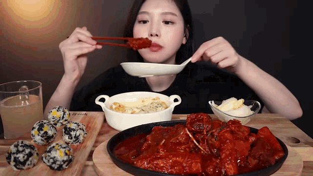 a woman is eating a plate of food with chopsticks and a bowl of food with the word rice on it