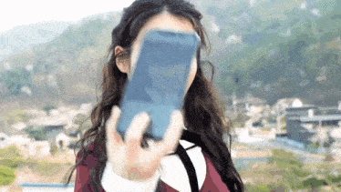 a woman is taking a selfie with a cell phone .