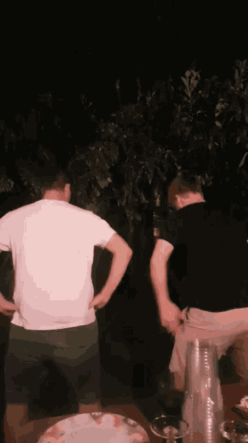 a man in a white t-shirt is standing next to a man in a black shirt