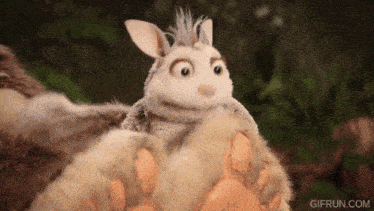 a stuffed animal that looks like a rabbit is being held by a large bear 's paw .