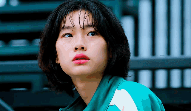 a close up of a woman wearing a green jacket with a white stripe