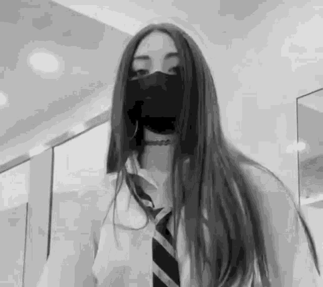 a black and white photo of a girl wearing a mask .