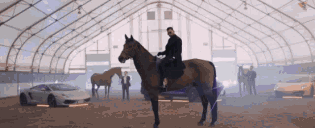 a man is riding a horse in a barn with cars behind him
