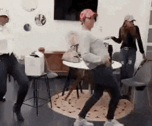 a group of people are dancing in a room in front of a table .