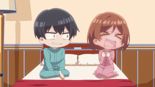 a boy and a girl are sitting on a bed and one of them is making a funny face