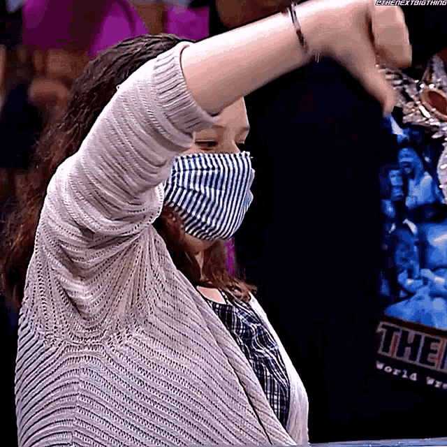 a woman wearing a face mask is standing in front of a sign that says the world wrestling