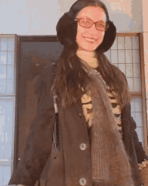 a woman wearing glasses and ear muffs is smiling for the camera