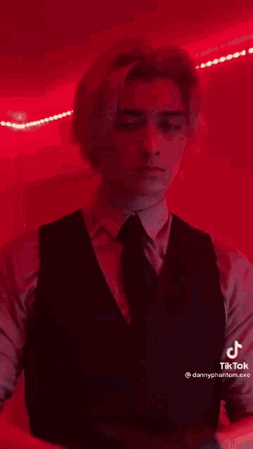 a young man in a suit and tie is standing in front of a red wall .