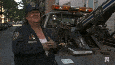 a man in a new york police uniform stands in front of a tow truck