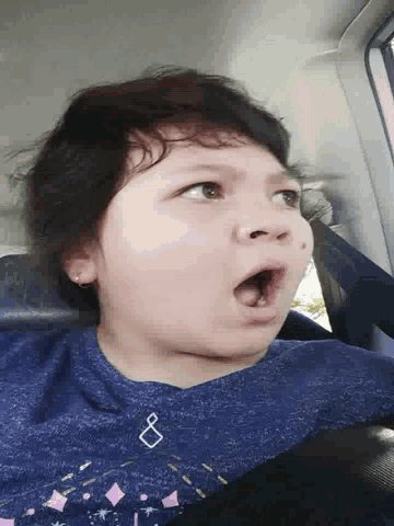 a girl wearing a blue shirt with a diamond on it is making a funny face
