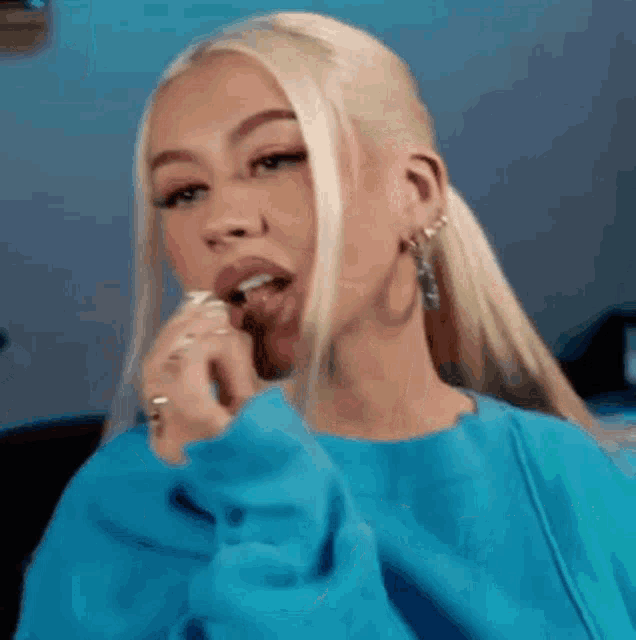 the woman is wearing a blue sweater and eating something .