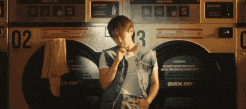a man sitting in front of a laundromat machine that says quick dry on it
