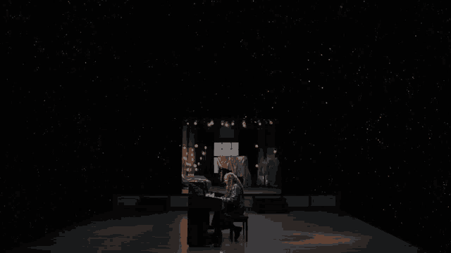 a woman sits at a piano in the dark