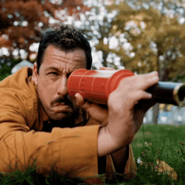 a man in a brown jacket is looking through a red object that says ' ucsd ' on it