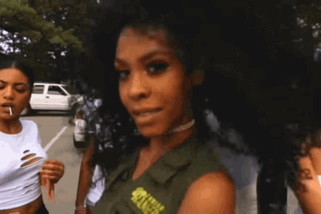 a woman wearing a green vest that says killer ranger blowing a bubble