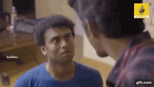 two men are talking to each other in a living room .