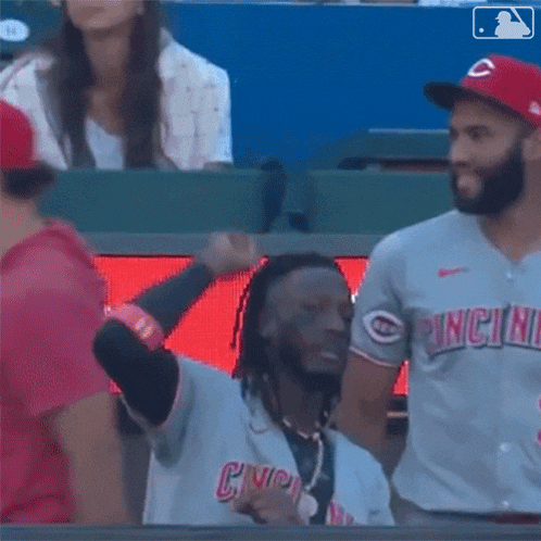 a baseball player in a cincinnati uniform is giving a peace sign .
