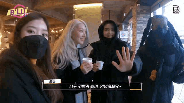 a group of women wearing face masks are standing next to each other holding cups of coffee