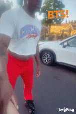 a man in a crop top and red pants is standing in front of a white car that says bts on it