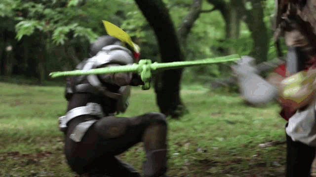 a man is holding a green stick in a forest