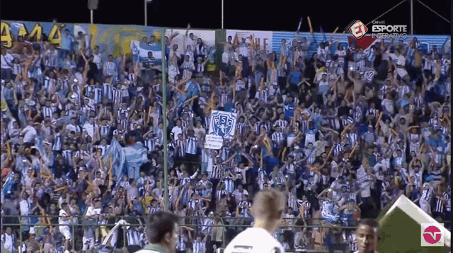 a crowd of people watching a soccer game with esporte written on the bottom