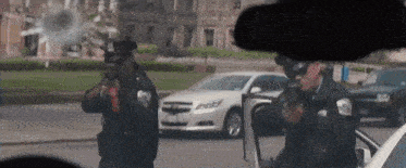 two police officers are standing in front of a white car