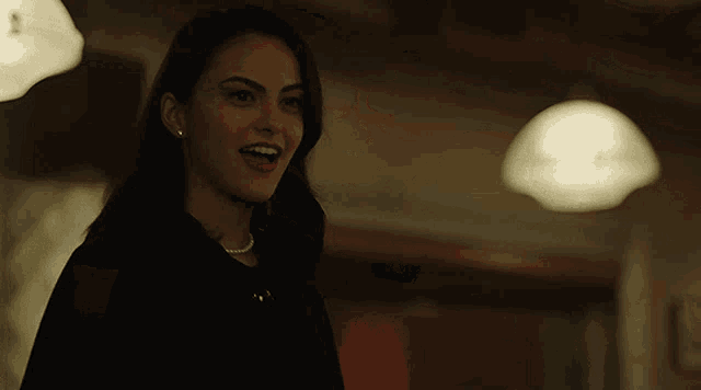 a woman in a black dress and white pearl necklace