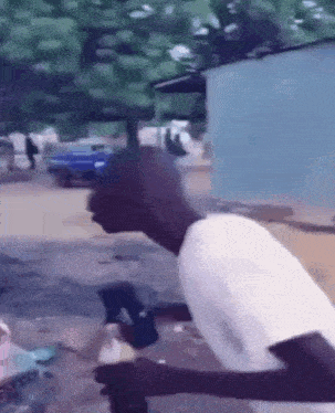 a man in a white shirt is holding a bottle of water and a hammer .
