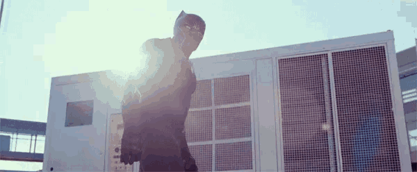 a man in a superhero costume is standing in front of a building holding a gun .