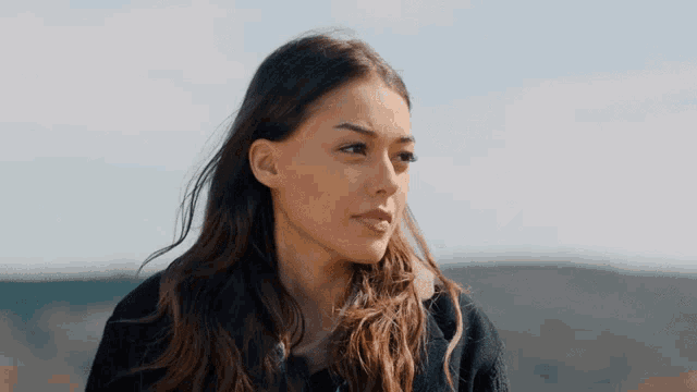 a woman in a black jacket looks at the camera